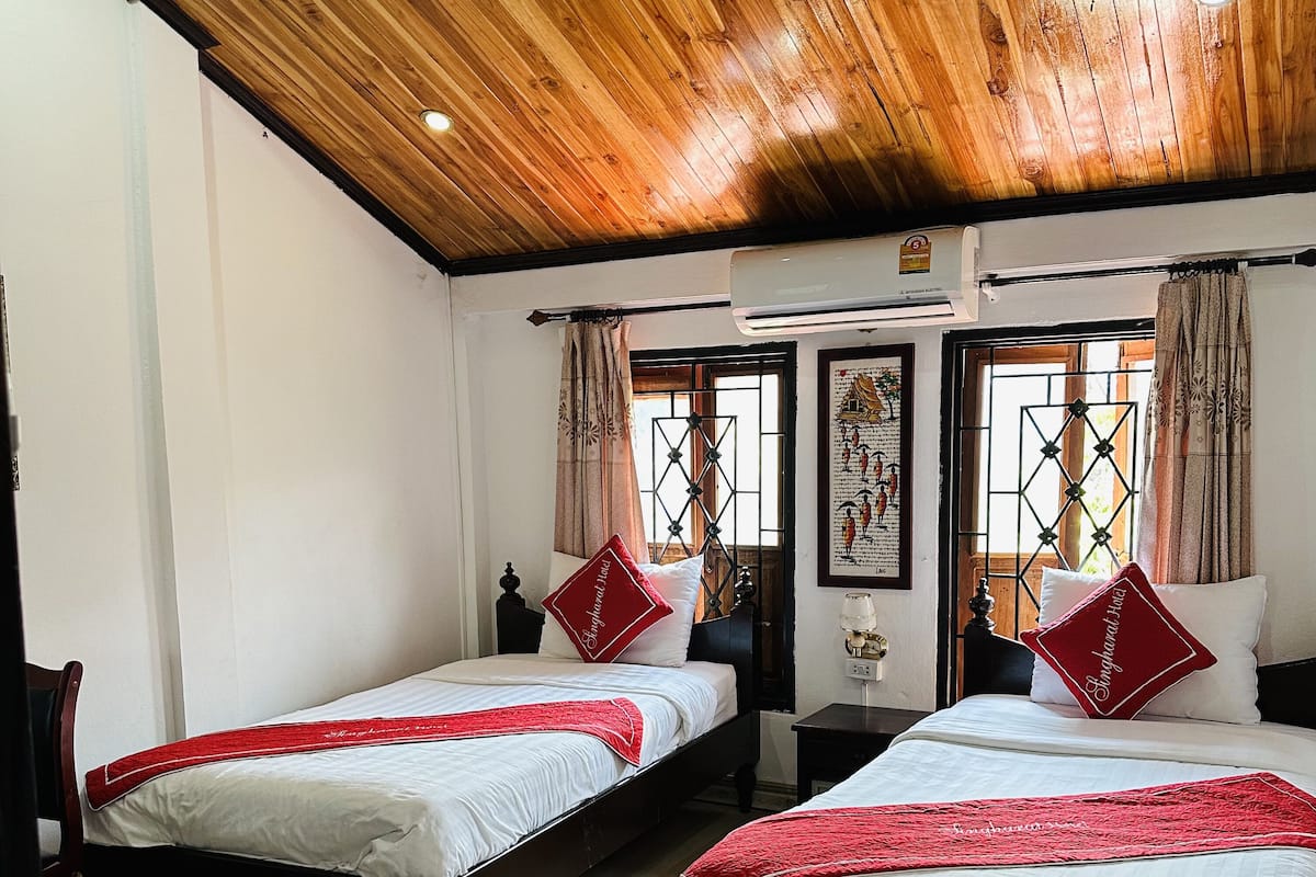 Une chambre d’hôtel avec deux lits, un plancher en bois et un plafond en bois.