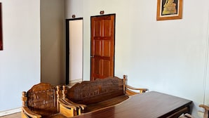 Una habitación con techo de madera, una amplia mesa de madera, dos sillas de madera, un sofá y una puerta.