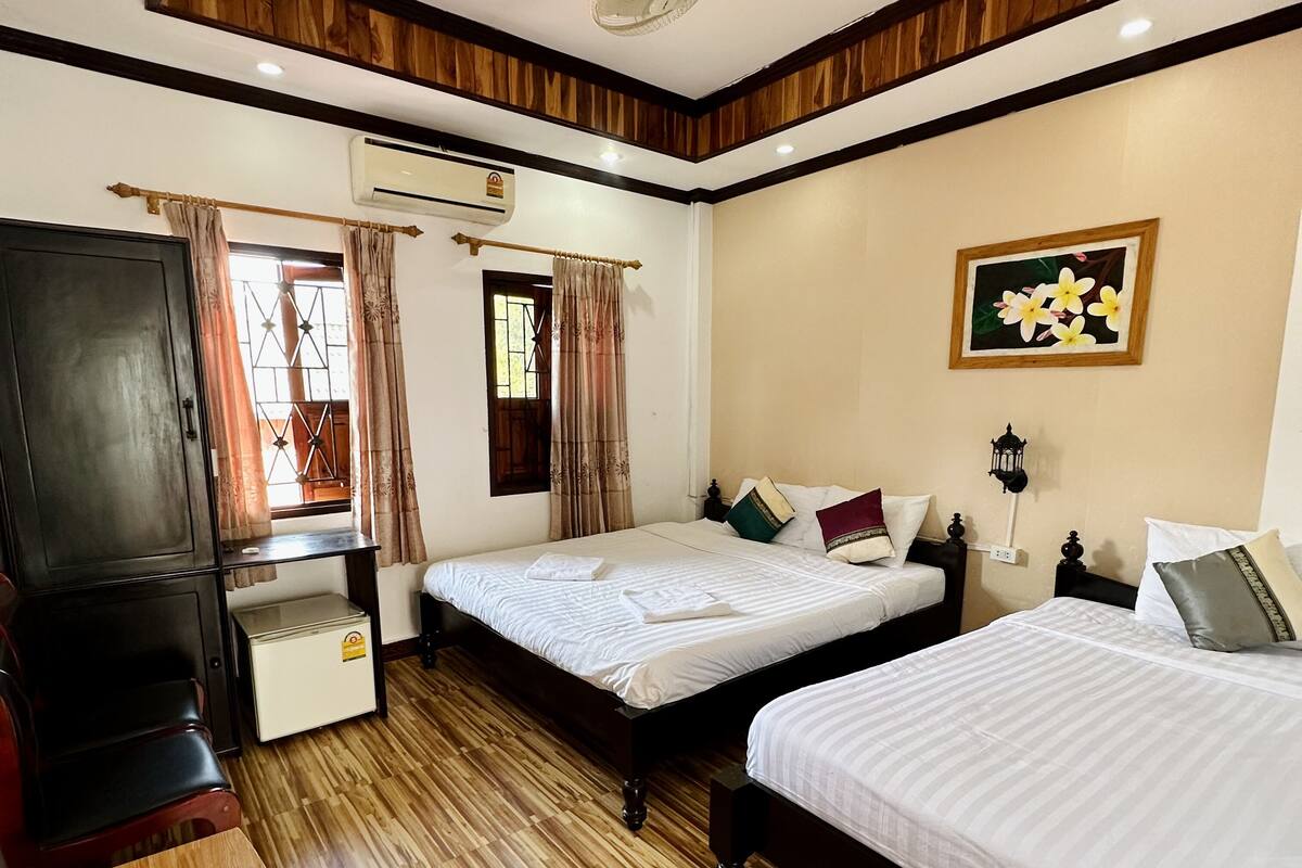Une chambre d’hôtel avec deux lits, un bureau, une armoire et un ventilateur de plafond.