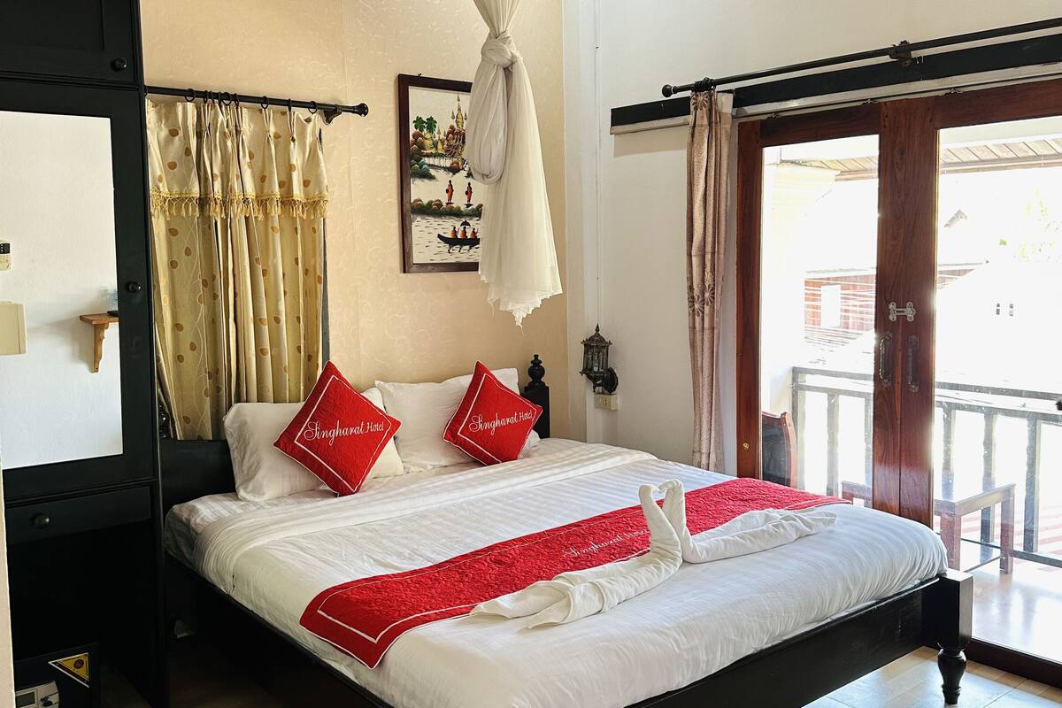 Une chambre d’hôtel avec un lit, un ventilateur de plafond, un appareil de climatisation et une vue sur l’extérieur.