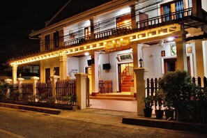A two-story building with a balcony and a sign indicating it is a guest house.