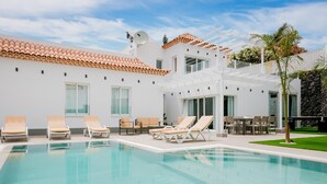 Ett modernt poolområde med solstolar och en pergola.