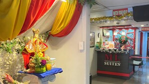 Un espace d’accueil d’hôtel agrémenté d’une décoration comprenant une statue, des plantes en pot et un panneau indiquant « MI SUITES ».