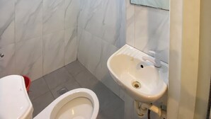 Une salle de bain avec des toilettes, un lavabo et une douche.