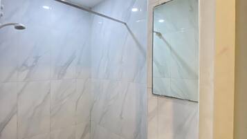 Een douche, pantoffels, een bidet, handdoeken