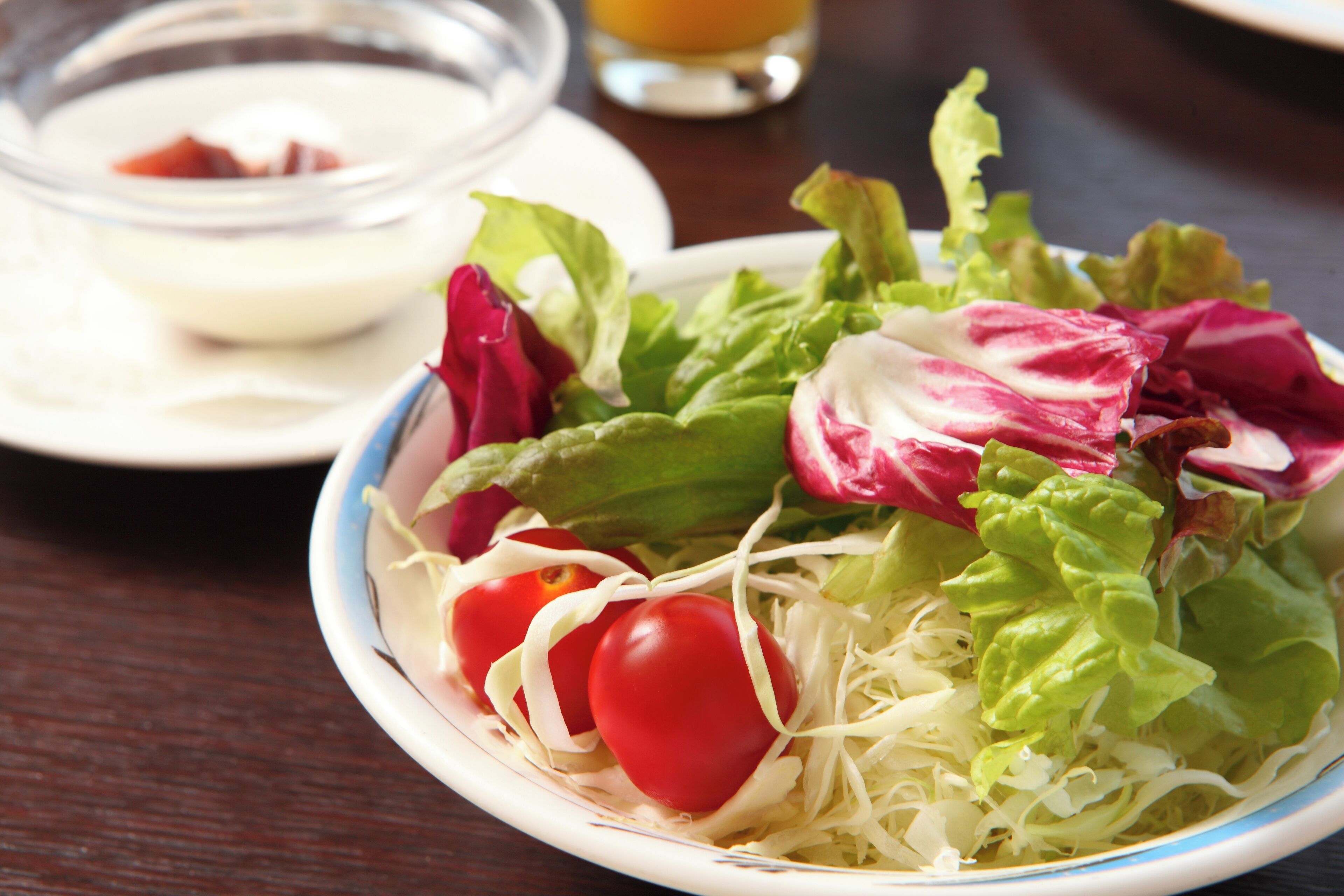 A salad with lettuce, shredded cheese, and cherry tomatoes on a plate.