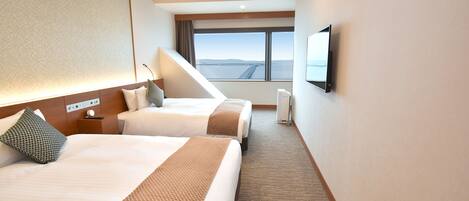 A hotel room with two beds, a large window with a view, a flat-screen TV, and a control panel on the wall.