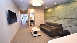 A hotel room with a large bed, a sofa, a TV, and a wall with abstract art.