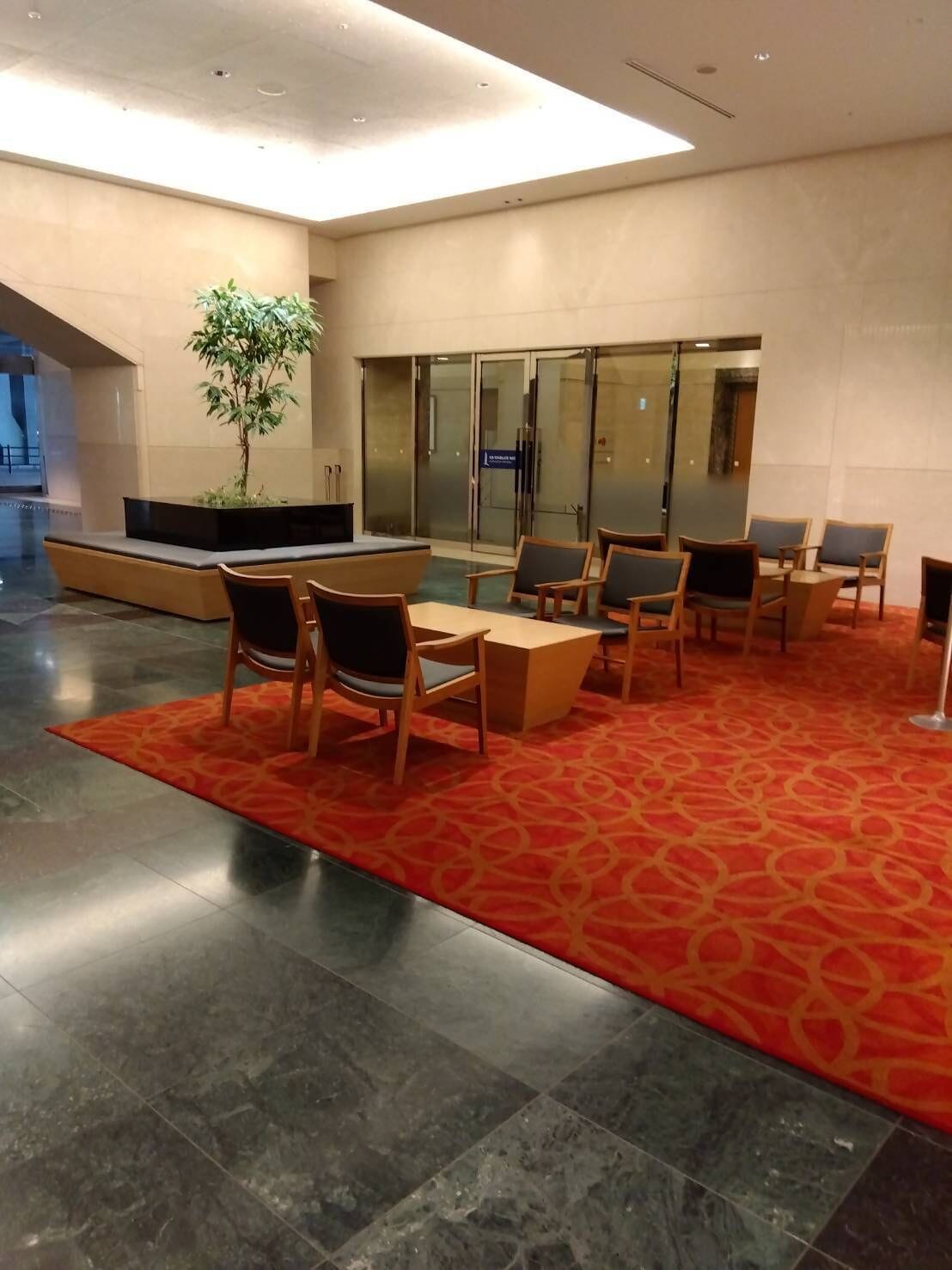 A lobby with a seating area, a plant, and a reception desk.