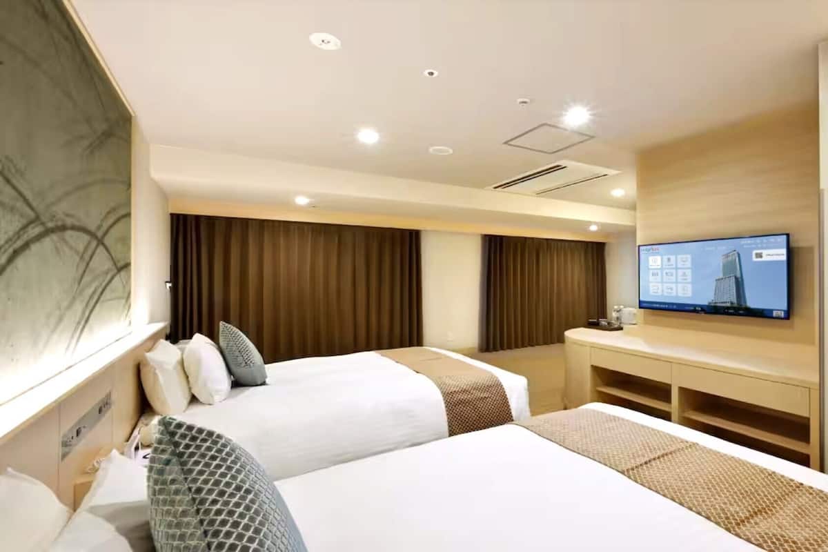 A hotel room with two beds, a TV, a desk, and a wardrobe.