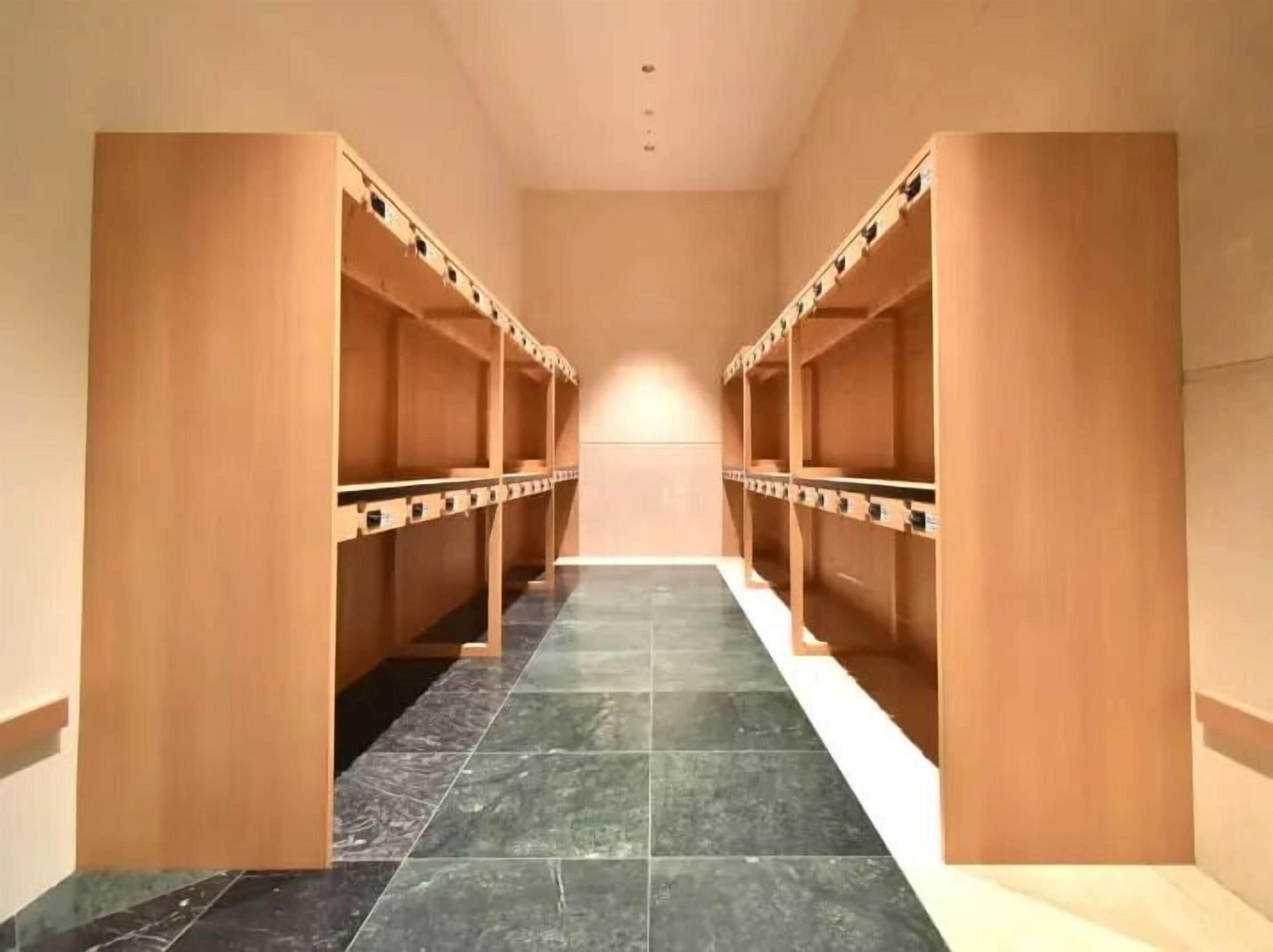 A corridor with wooden lockers on either side and a tiled floor.