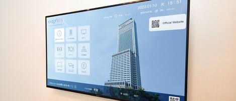A digital display of the Odyasis Suites Osaka Airport Hotel with a modern building and various hotel amenities icons.