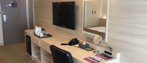 Une chambre d’hôtel équipée d’un bureau, d’un miroir, d’une télévision et d’une porte.