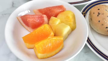 A plate with watermelon, pineapple, and orange slices, and a small round bread with seeds.