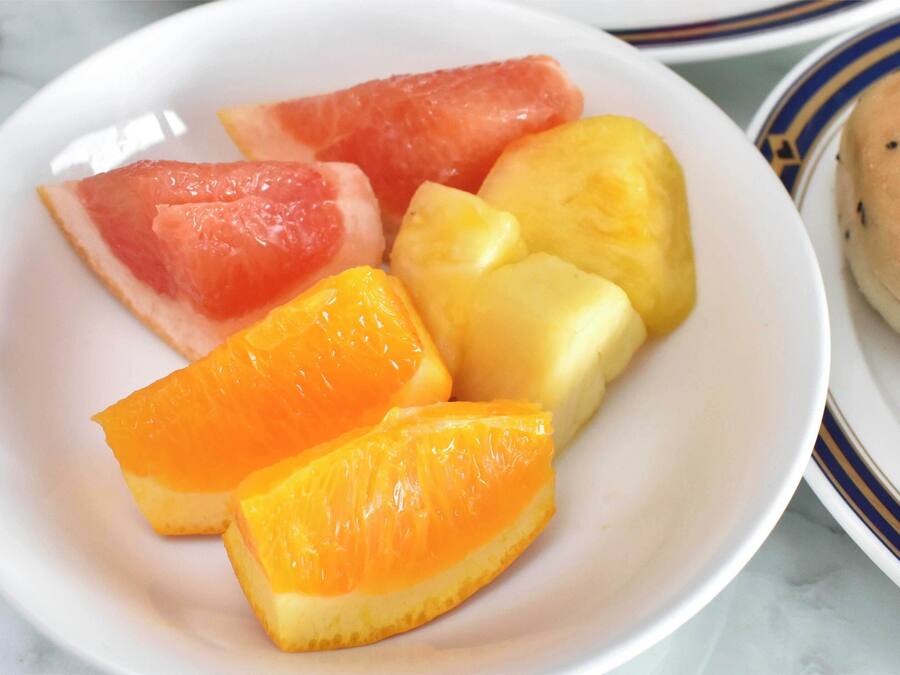 A plate with watermelon, pineapple, and orange slices, and a small round bread with seeds.