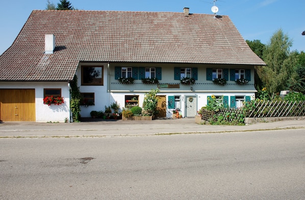A two-story building with a tiled roof, a wooden door, and flower boxes on the windows. - HOLIDAY APARTMENT IN THE ALLGÄU, 10 minutes from Center Park (Altusried)