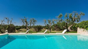 A clear blue swimming pool with two sun loungers and a lantern. - 339 I Trulli di Nanì by Perle di Puglia (Ostuni)