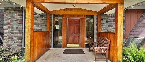 A wooden porch with a door, a bench, and a stone wall.