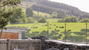 A patio with metal chairs and a table, overlooking a green field with sheep. - Dolwen (Betws-Y-Coed)