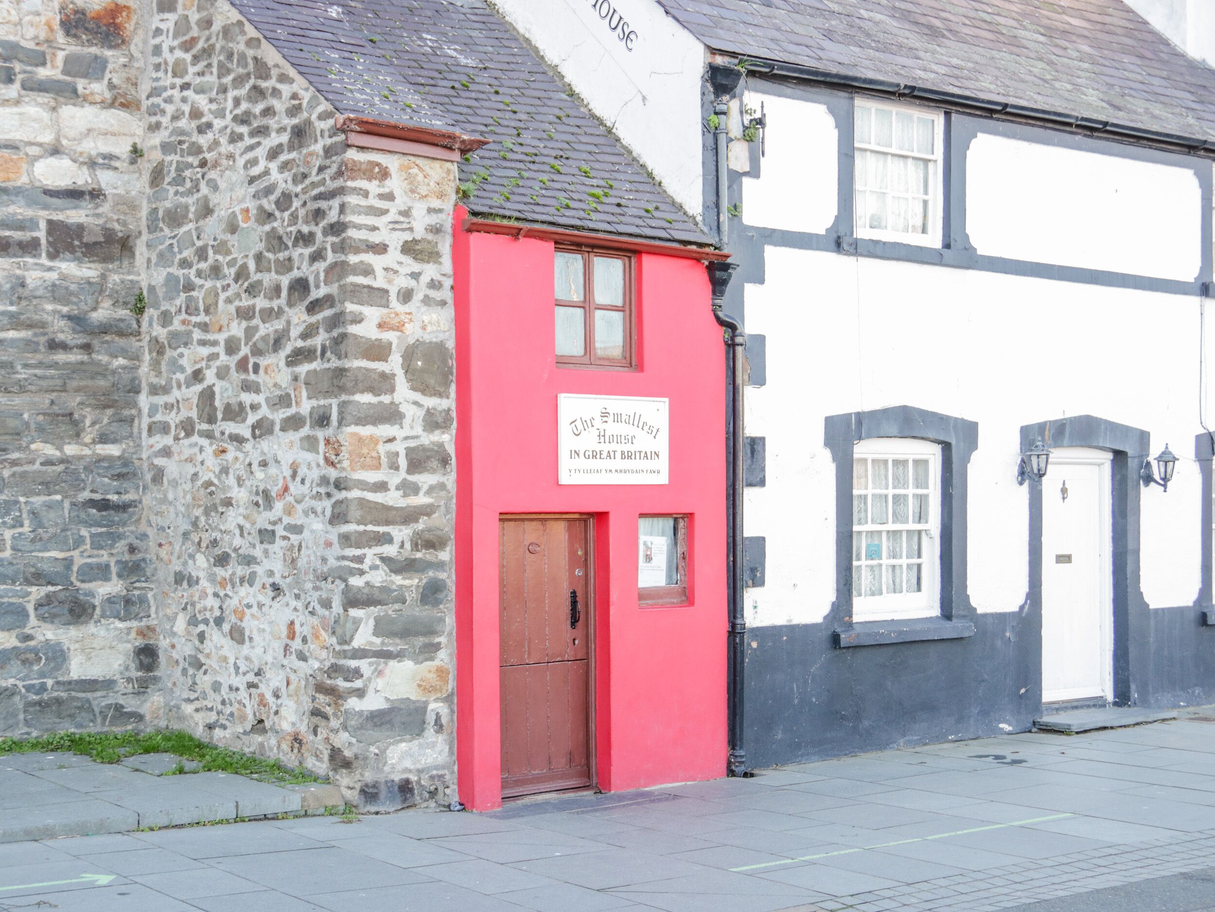 A stone building with a red door and a sign that reads "The Smallest House in Great Britain."