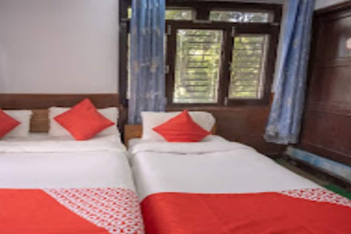 Une chambre avec deux lits, chacun recouvert d’une courtepointe rouge et blanche, assortie aux coussins.