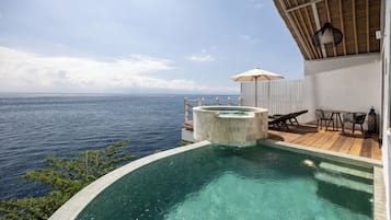 Une piscine avec vue sur l’océan, un jacuzzi et un espace salon extérieur.