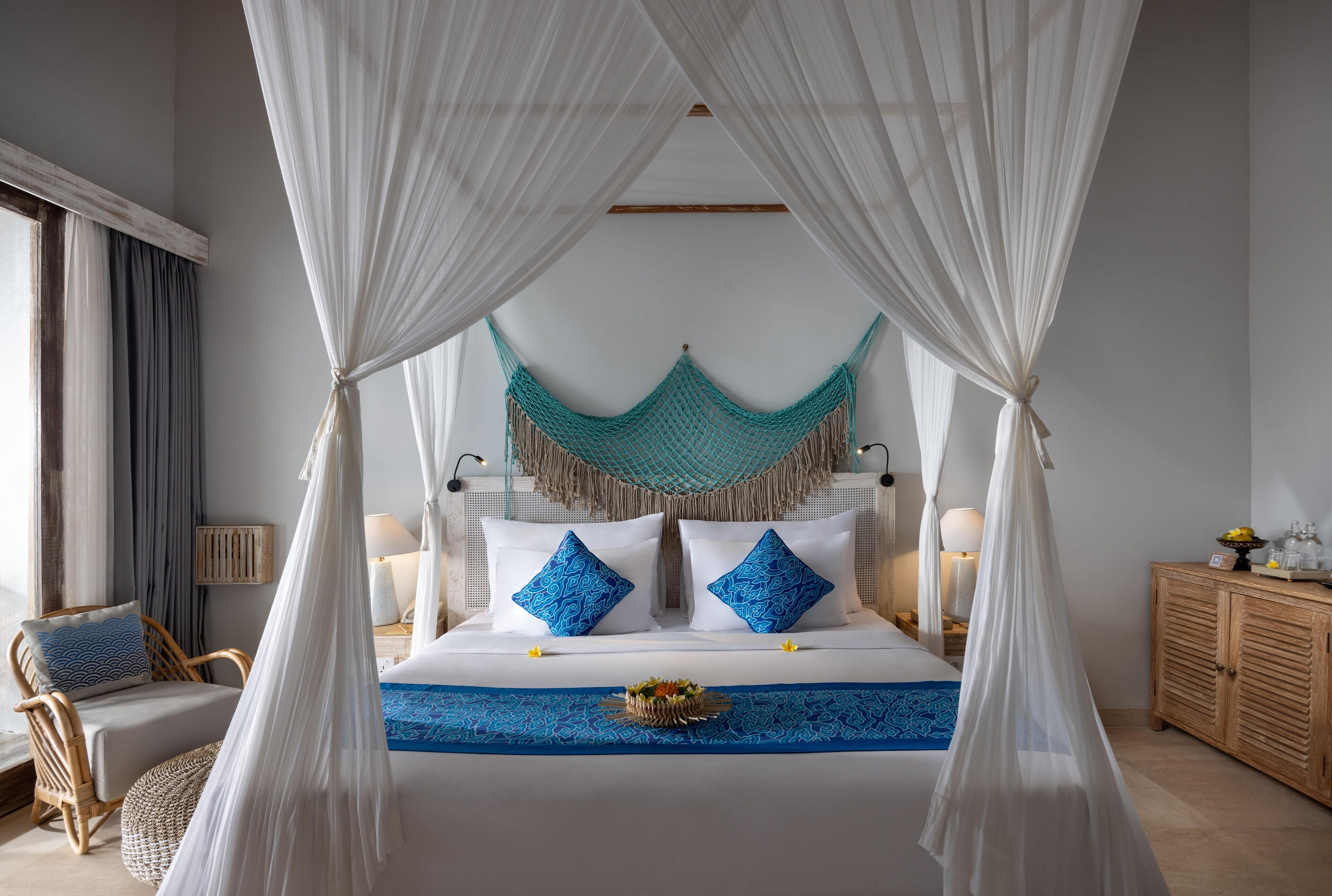 A bed with white and blue bedding, a canopy, and a decorative hanging net.