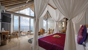Un dormitorio amplio con una cama grande, un escritorio y vistas al océano.