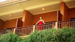 A person standing on a balcony with a brick building in the background. - Mere Sea View Penida (Penida Island)