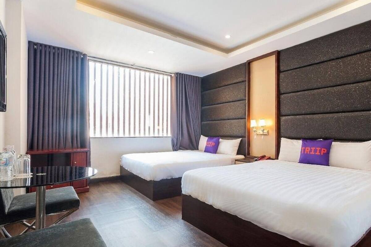 A hotel room with two beds, a desk, and a window with curtains.