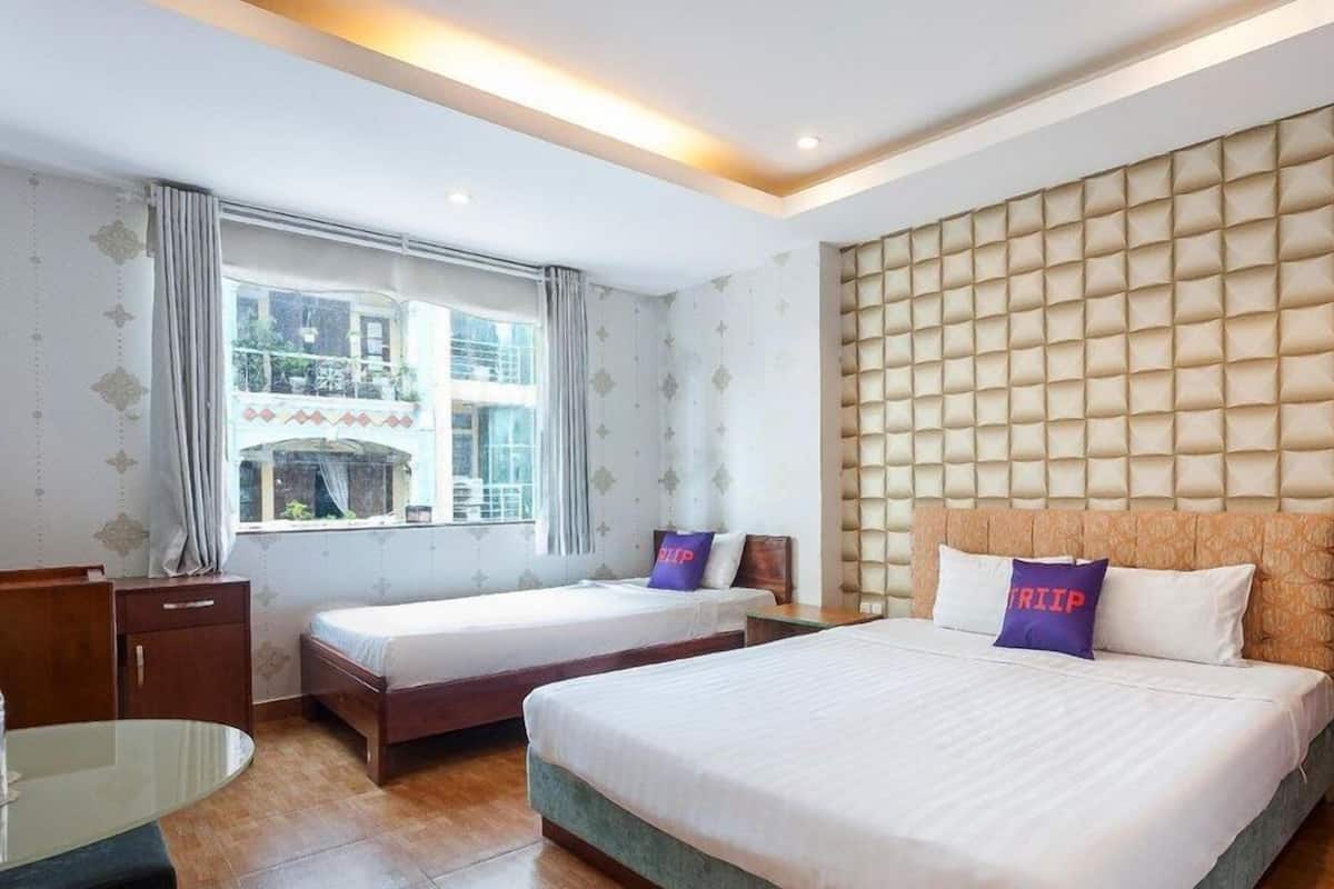 A hotel room with two beds, a desk, and a large window.
