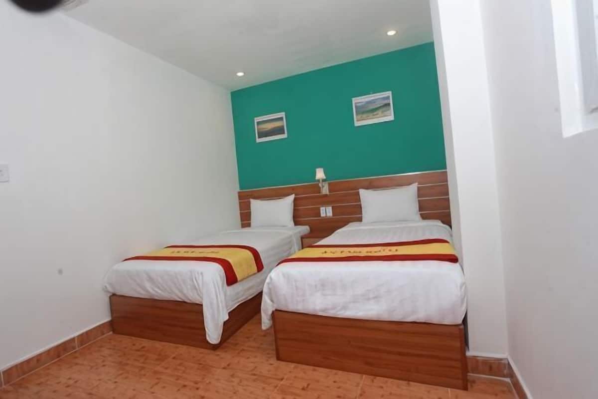 A room with two beds, wooden headboards, white bedding, and a teal accent wall.