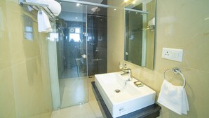 A modern bathroom with a glass-enclosed shower, a large mirror, and a white sink. - The Beacon Hotel Visakhapatnam (Visakhapatnam)