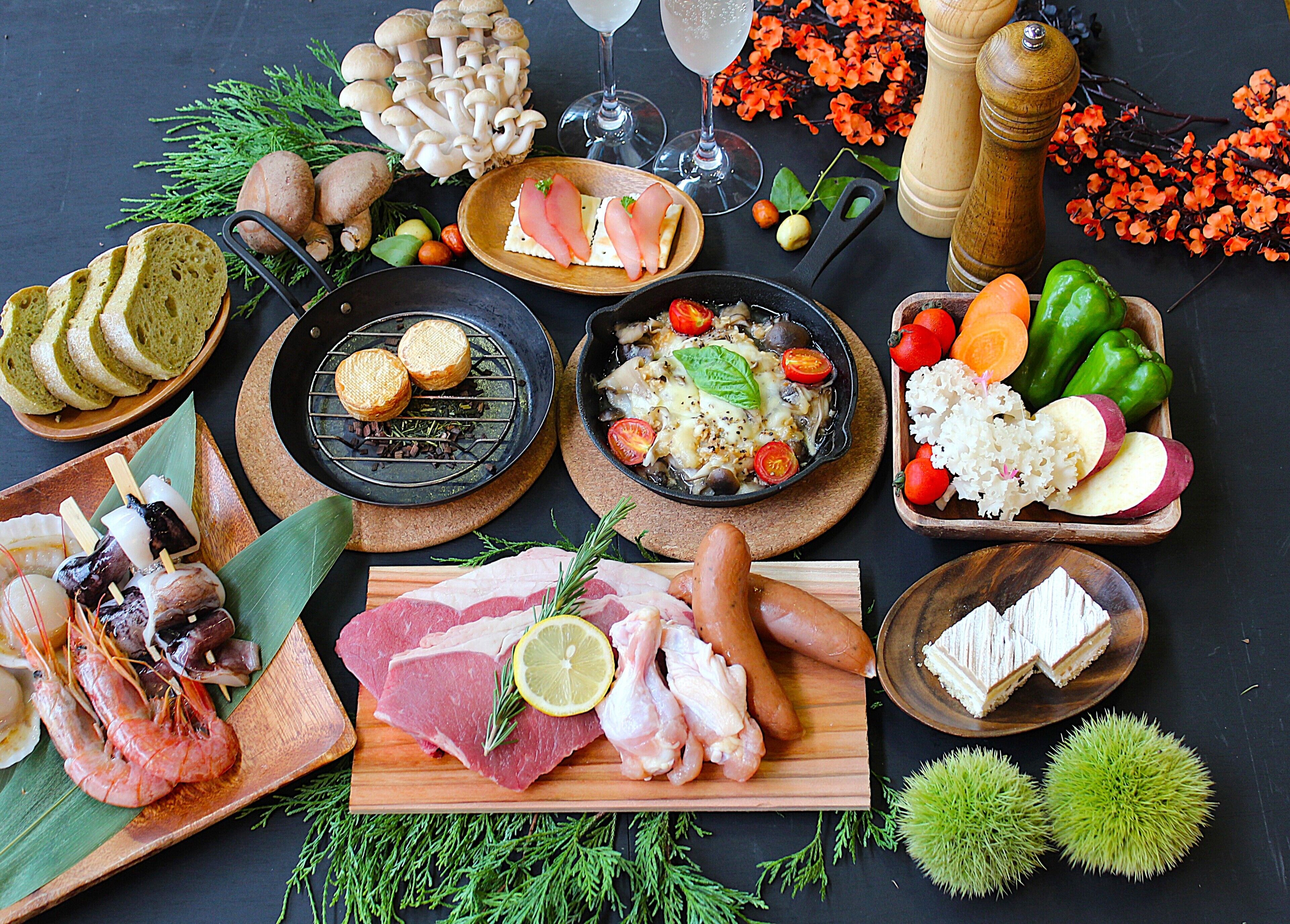 Diversos alimentos y condimentos dispuestos sobre una mesa, entre ellos carnes, quesos y verduras.