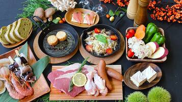 Diversos alimentos y condimentos dispuestos sobre una mesa, entre ellos carnes, quesos y verduras.