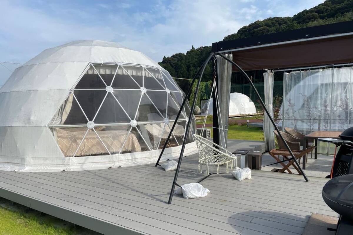 A geodesic dome structure with a swing set and outdoor seating area on a wooden deck.