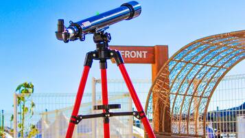 A telescope on a red tripod in an outdoor area with a sign that reads "FRONT".