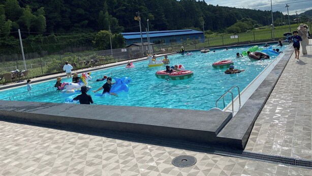 A swimming pool with inflatable rings, surrounded by a tiled deck and a fence. - Glamping & Port (Shimada)