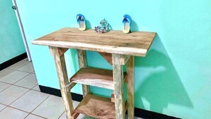 A wooden table with two blue slippers on top, a small decorative item, and a tiled floor.