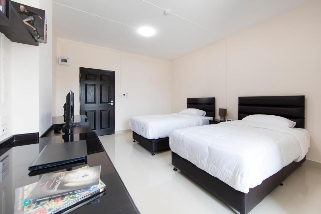 A hotel room with a large bed, a smaller bed, a desk with a laptop, and a TV.