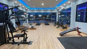Ein Fitnessstudio mit Trainingsgeräten, Holzböden und großen Fenstern.