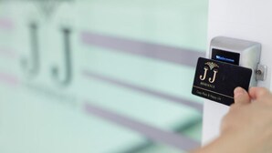 Eine Hand hält eine Karte mit dem Schriftzug 'JJ RESIDENCE' und 'Easy Place & Happy Life', die in einen Kartenleser eingeführt wird.