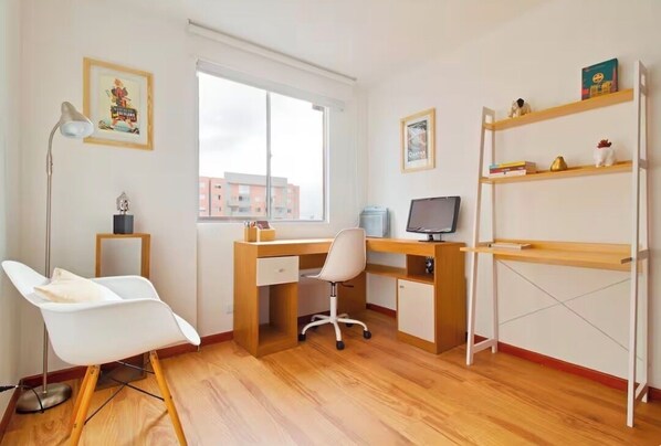 Une pièce comprenant un bureau, une chaise, des étagères et une fenêtre.