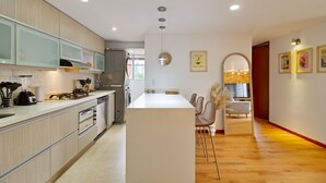 Une cuisine moderne dotée d’un îlot central, d’appareils électroménagers intégrés et d’un coin repas avec des chaises et une table.