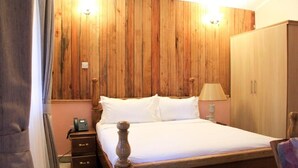 Une chambre aux murs lambrissés, avec un lit, une lampe de chevet et une armoire.