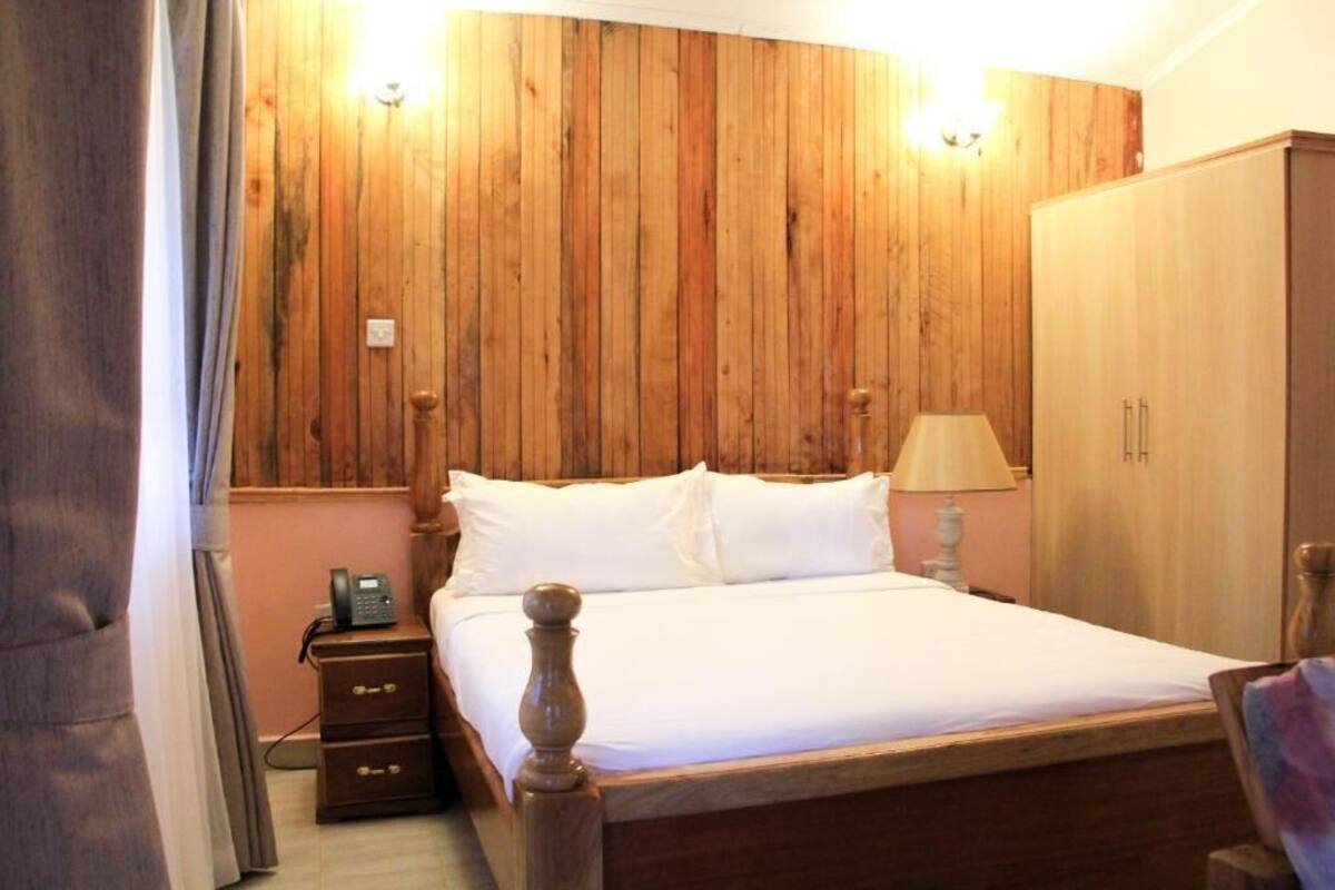 A wooden-paneled bedroom with a bed, bedside lamp, and a wardrobe.