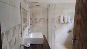 Une salle de bain avec un lavabo blanc, une cabine de douche en verre et un sol carrelé.