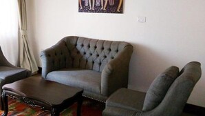 Un salon avec un canapé capitonné, une petite table et un tableau accroché au mur.
