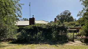 A house with a brick chimney, surrounded by lush greenery and a garden area with a wooden pergola. - Family farm retreat, big outdoor alfresco areas, with emus (Barwidgee)