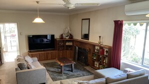A living room with a TV, sofas, a coffee table, a fireplace, and a bookshelf. - Family farm retreat, big outdoor alfresco areas, with emus (Barwidgee)